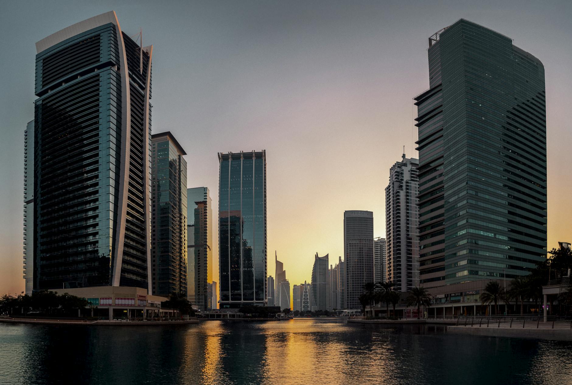 Stunning view of Dubais modern skyline reflecting at sunset, showcasing iconic architecture.